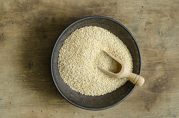 Bowl of quinoa with wooden shovel on wood Photograph by Westend61