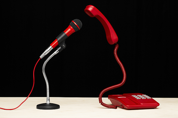 A telephone and microphone facing each on a desktop Photograph by Creative Crop