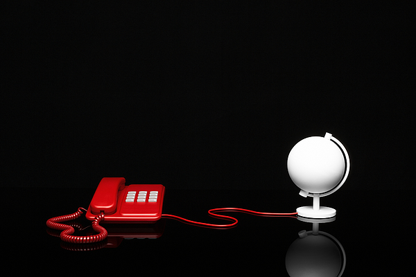 A telephone is connected to a desk globe via a cable Photograph by Creative Crop