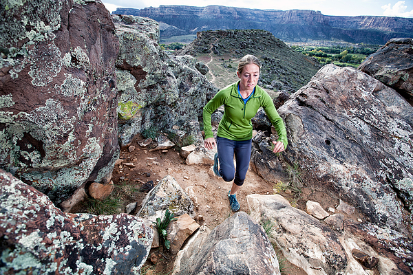 An adult woman trail running on a remote dirt trail Photograph by Robb Reece