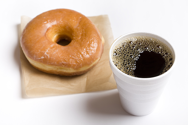 Close-up of a cup of black coffee and a glazed donut Photograph by Blueflames