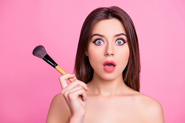 Close up portrait of shocked beautiful attractive pop-eyed pretty surprised scared make up artist holding a brush for blusher and powder in a hand, isolated on pink background Photograph by Deagreez