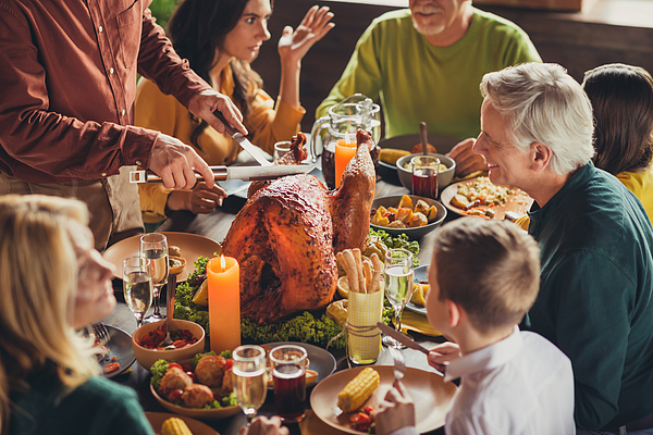 Cropped photo of family meeting served table thanks giving dinner two knives slicing stuffed turkey meal living room indoors Photograph by Deagreez