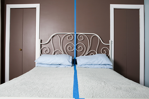 Double bed separated by blue line Photograph by Image Source