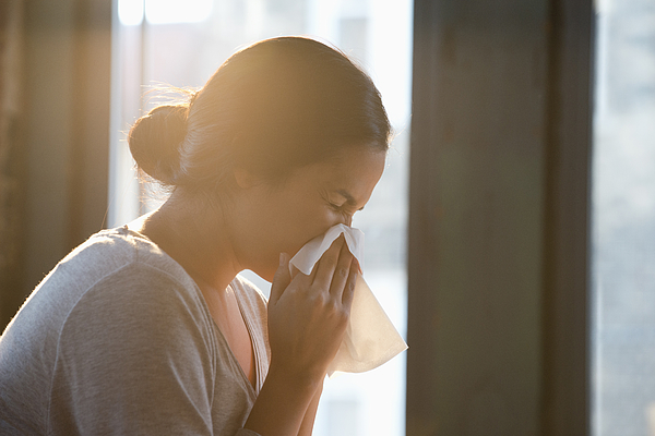 Hispanic woman wiping nose with tissue Photograph by Jose Luis Pelaez Inc
