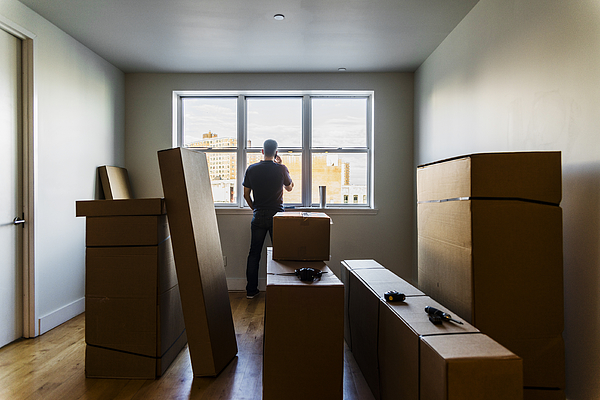 Moving in! The mature Caucasian man talking by phone nearby the window in the empty living room filled with cardboard boxes, in the new house. Photograph by Alex Potemkin Moving in! The mature Caucasian man talking by phone nearby the window in the empty living room filled with cardboard boxes, in the new house. Photograph by Alex Potemkin
