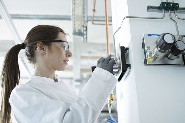 Side view of woman in workshop wearing safety goggles and coat adjusting control panel Photograph by Sigrid Gombert Side view of woman in workshop wearing safety goggles and coat adjusting control panel Photograph by Sigrid Gombert