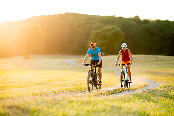Smiling Sporty Couple On Mountain Bikes In Rural Landscape Photograph by Amriphoto