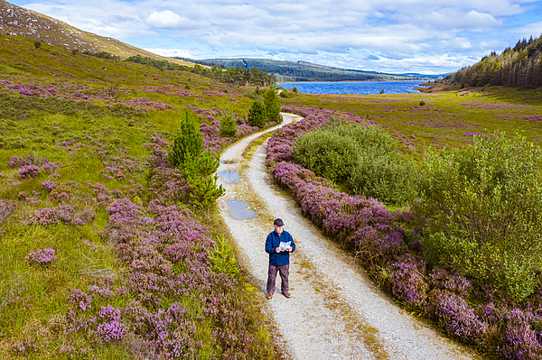 The high angle view of an active senior man looking at a map while standing on a dirt road in a remote part of Dumfries and Galloway, south west Scotland Photograph by JohnFScott The high angle view of an active senior man looking at a map while standing on a dirt road in a remote part of Dumfries and Galloway, south west Scotland Photograph by JohnFScott