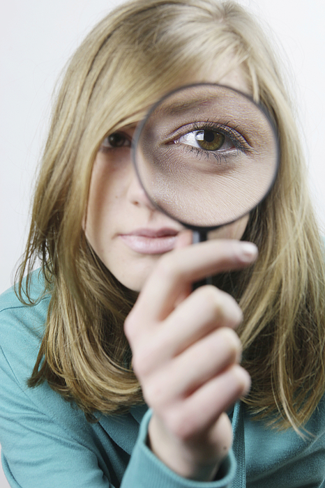 Young woman with magnifying glass in front of her eye Photograph by Scully