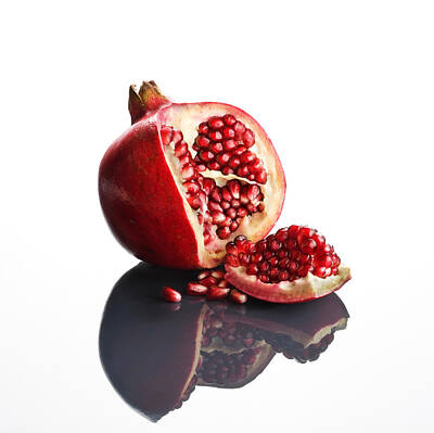 Food And Beverage Royalty-Free and Rights-Managed Images - Pomegranate opened up on reflective surface by Johan Swanepoel