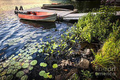 Lilies Photos - Rowboat at lake shore at dusk by Elena Elisseeva