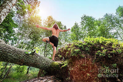 Athletes Royalty Free Images - Young man standing on a tree trunk in the forest. Royalty-Free Image by Michal Bednarek