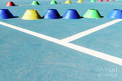 Studio Grafika Typography - Colorful plastic cones on a blue cement tennis court with white  by Joaquin Corbalan
