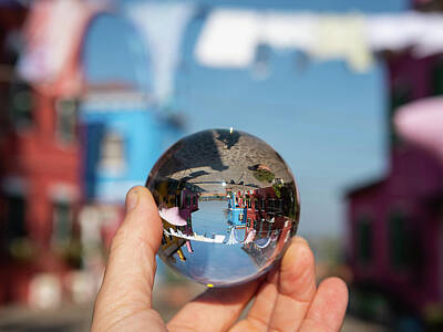 Lighthouse - Hand holding glass sphere in front of colorful houses by Stefan Rotter