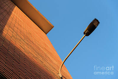 Beaches And Waves - A deep red brick wall supports a lamppost, contrasting and brigh by Joaquin Corbalan