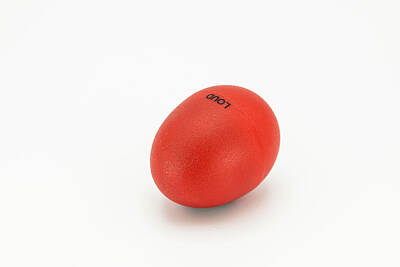 Painted Wine - A red egg shaker lying on a white underground by Stefan Rotter