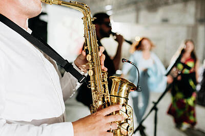 Jazz Photo Royalty Free Images - Concert view of a saxophone player with vocalist and musical jazz band in the background Royalty-Free Image by Maria Kray